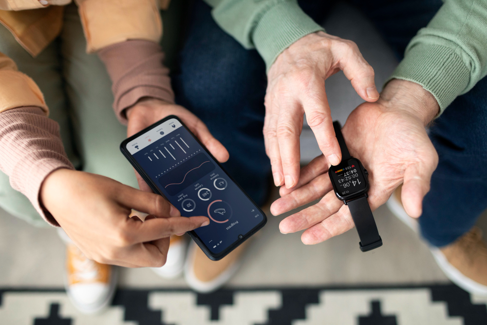Deux personnes ragardent un teléphone connecté et une montre connectée.
